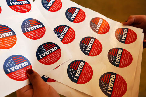 Close-up of several stickers on a white sheet that read, 'I Voted'