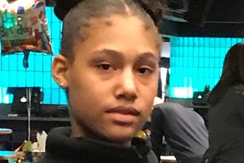 CLose-up of Black teen girl wearing two buns in her hair and gold stud earrings in her ears. 