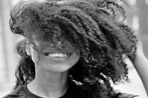 Lianne La Havas album cover displays a Black and white image of Lianne La Havas smiling with one hand in her natural hair which is covering half of her face.