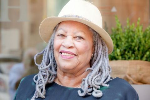 Brown skinned, older woman with white locs and a straw hat on top, smiling