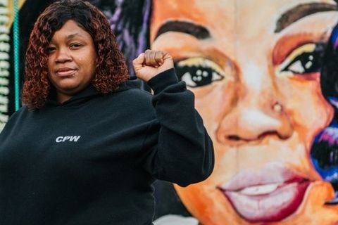 Breonna Taylor's mother, Tamika Palmer, raises her fist in salute, in front of her daughter's mural.