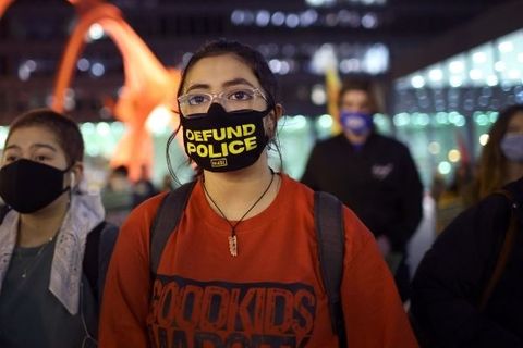 Image of woman wearing "defund police" face mask