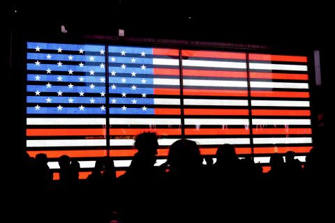 An image of the American flag with the silhouettes of people standing in front of it