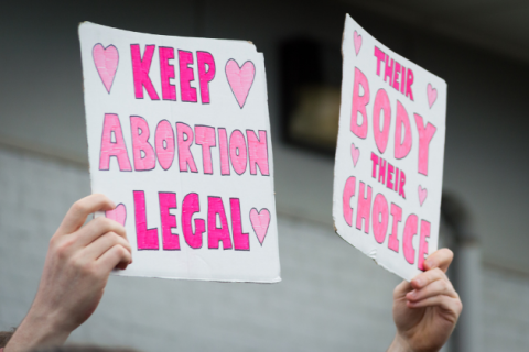 Pro-choice Planned Parenthood demonstration holding two signs that read "Keep Abortion Legal" and "Their Body Their Choices"