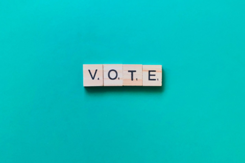 Vote written in scrabble letters on a blue background